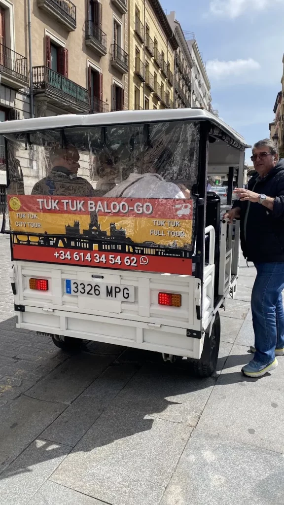 Parte trasera de un tuk tuk de Baloo-Go rotulado con el teléfono de contacto de Madrid y un sello circular