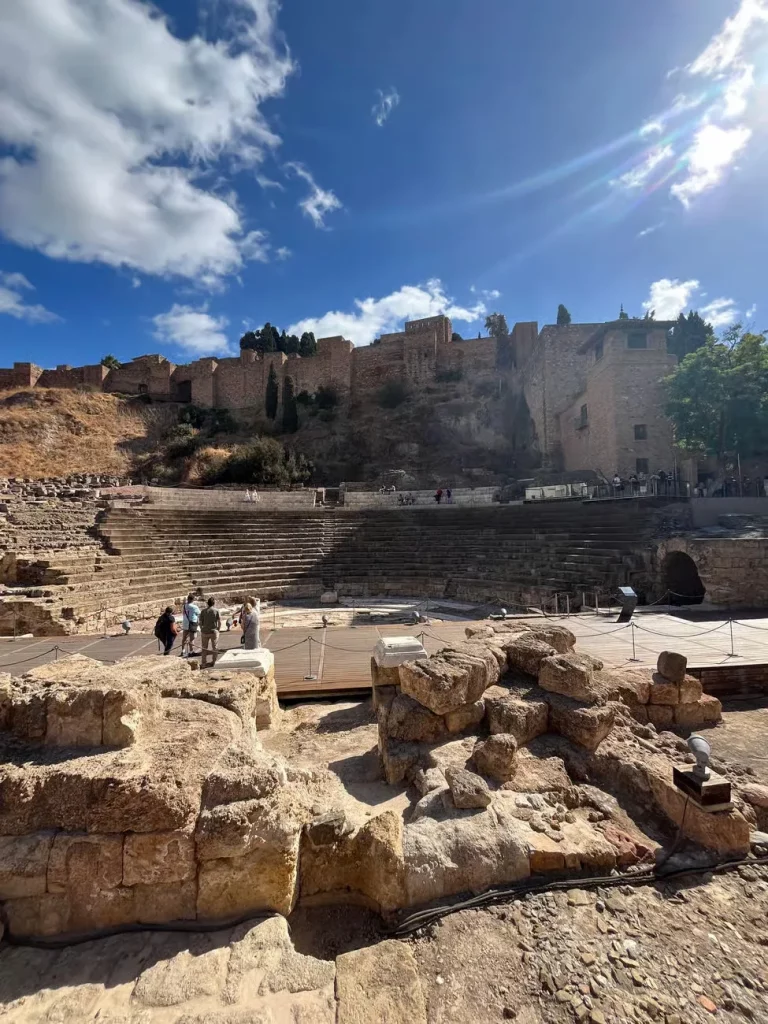 Teatro Romano de Málaga con la Alcazaba al fondo bajo un cielo azul