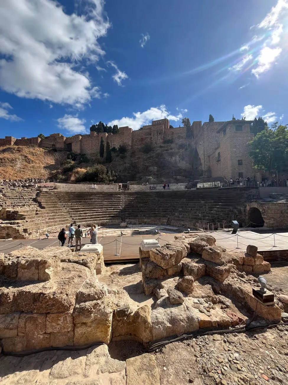 Teatro Romano de Málaga con la Alcazaba al fondo bajo un cielo azul